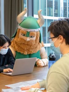 PSU mascot Victor E. Viking with students in the PSU Library in 2021
