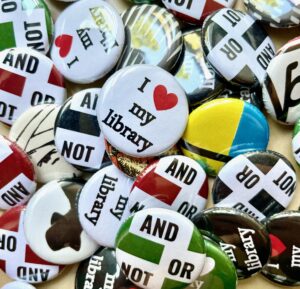 A pile of novelty buttons with library-related messages like "I heart my library" and "And Or Not".