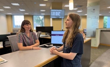 A student speaking with a reference librarian at the 1st floor reference desk