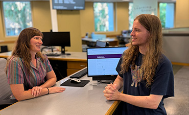 A student speaking with a reference librarian at the 1st floor reference desk