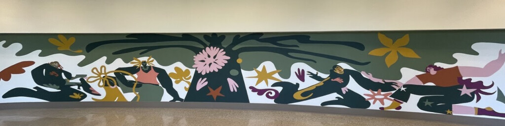 A colorful mural of people dancing under the limbs of a tree.